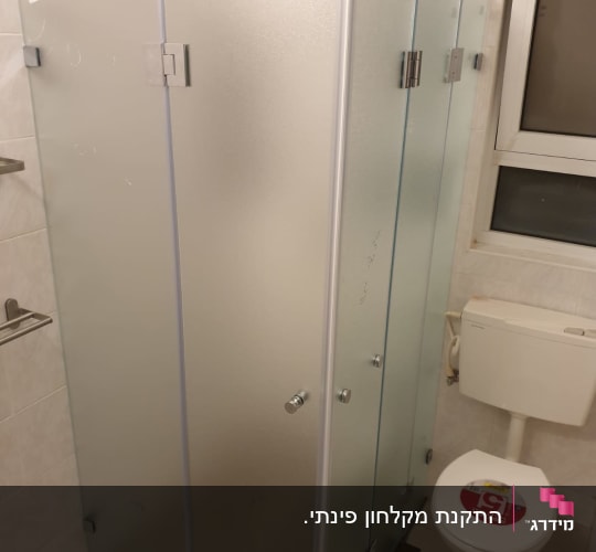 מקלחון זכוכית עם דלתות מתכת בחדר אמבטיה